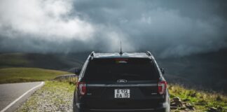 Czarny SUV na szutrowym poboczu, w tle góry pod chmurami