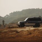 Mitsubishi Pajero jedzie szutrową drogą wśród wzgórz i drzew