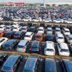 Nowe samochody ustawione w równych rzędach na dużym parkingu