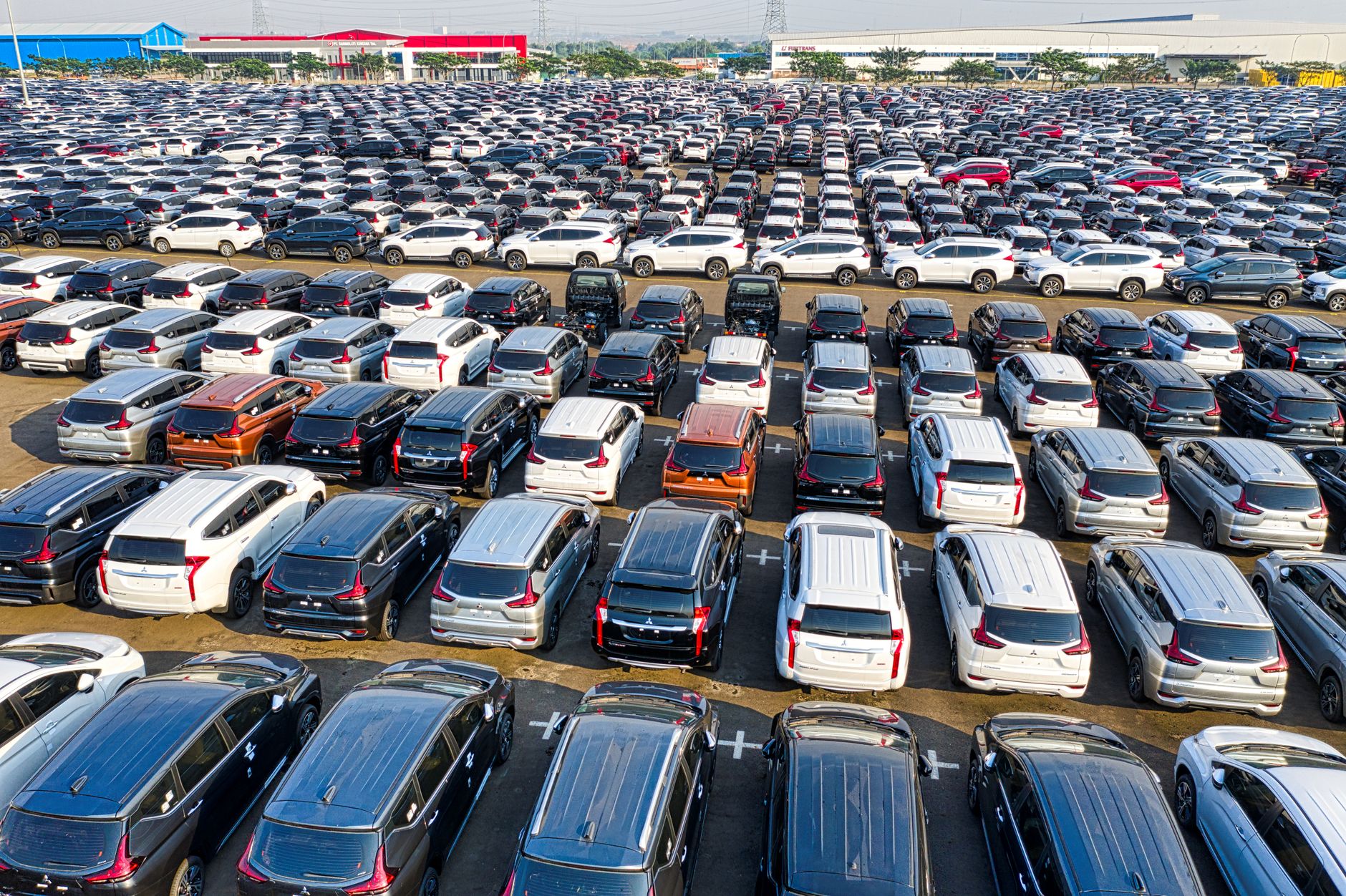 Nowe samochody ustawione w równych rzędach na dużym parkingu