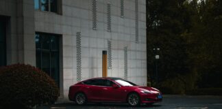 Samochody premium z napędem elektrycznym, które zmieniają rynek motoryzacyjny Czerwony luksusowy samochód elektryczny przy nowoczesnym budynku